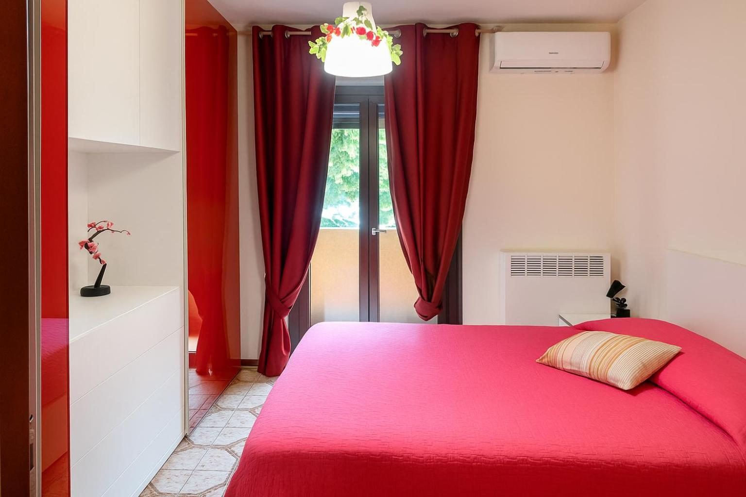 The double bedroom with a fuchsia bedspread and red curtains