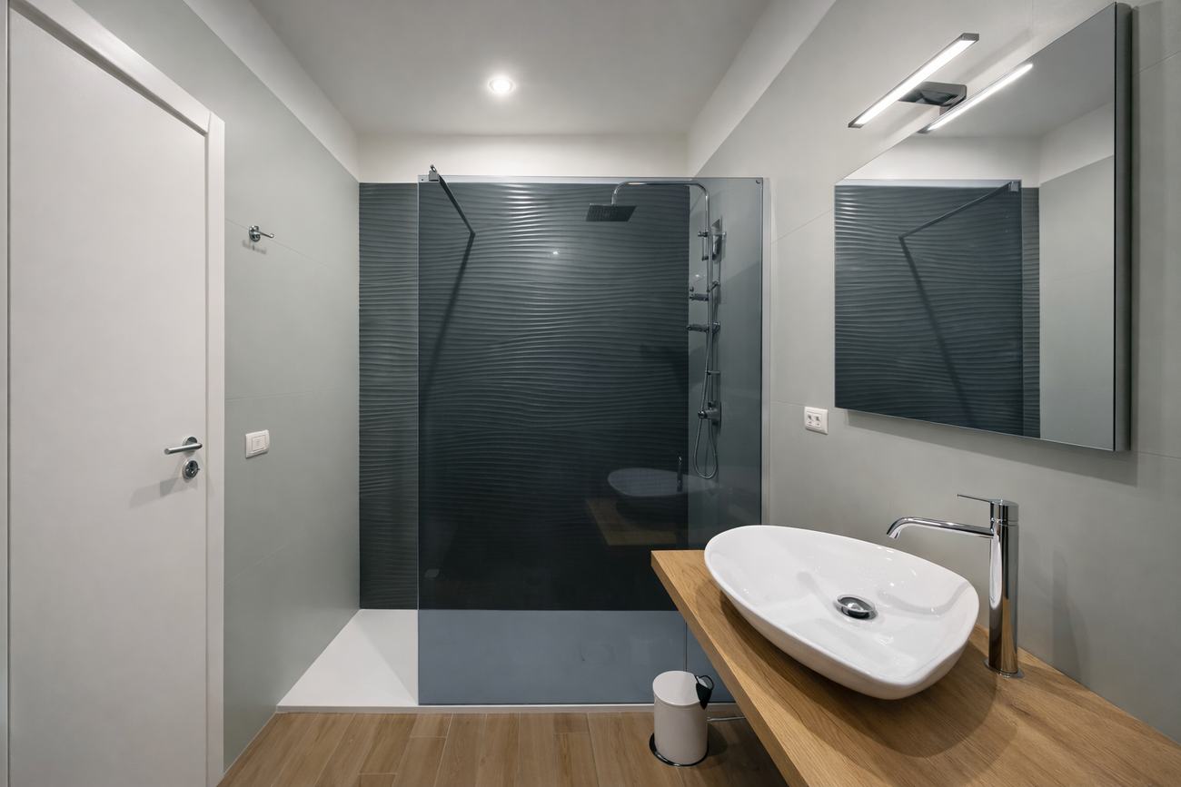 Bagno grigio con doccia a filo pavimento e lavabo d’appoggio