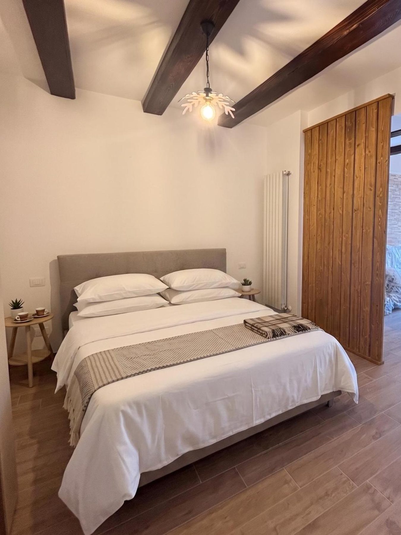 The bedroom: double bed, dark beams and a slatted wooden wall