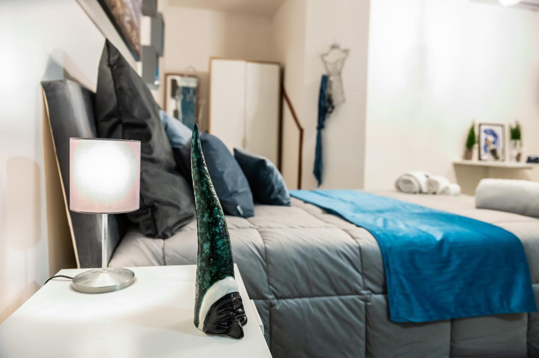 The bed with dark cushions and the bedside lamp