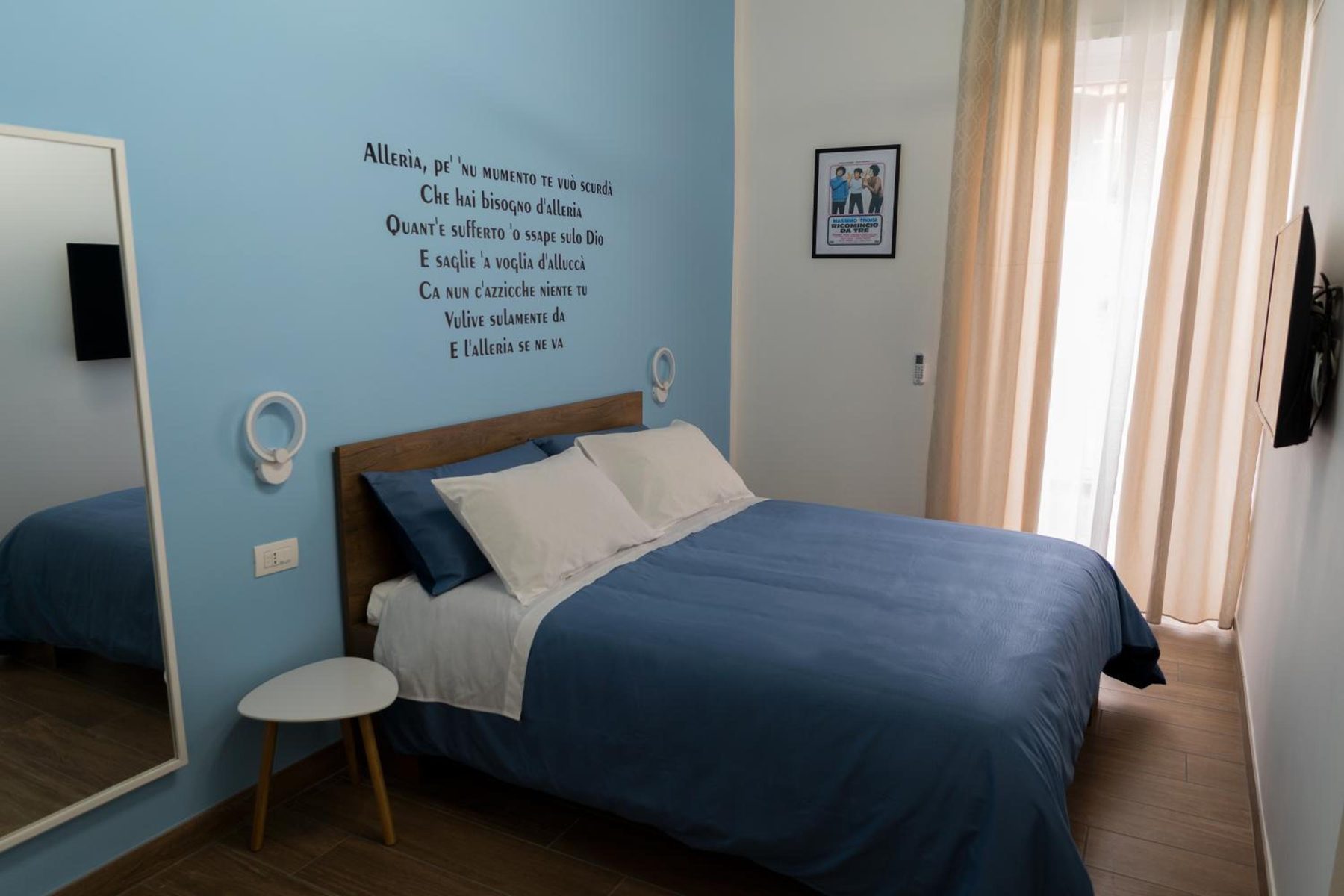 Alleria: blue double bed, pale blue wall and light from the window
