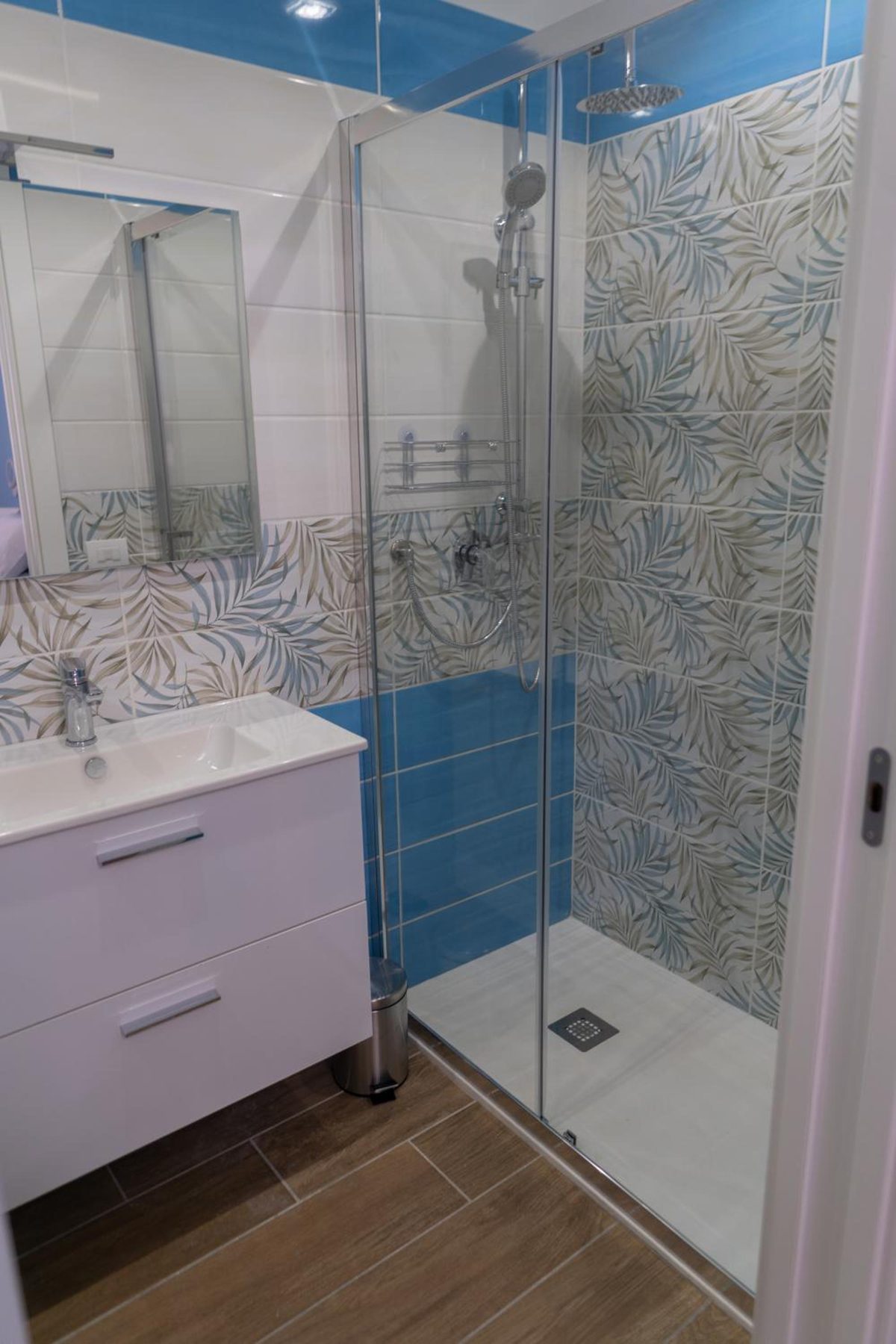 Bathroom with a glass shower and leaf-patterned tiles