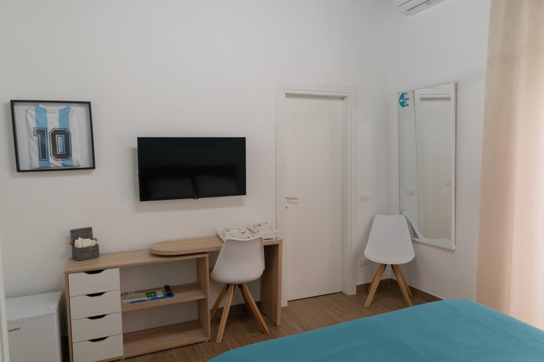 The desk with the TV, by the door